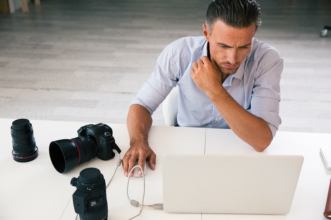 Portrait,Of,A,Photographer,Using,Laptop,At,His,Workplace