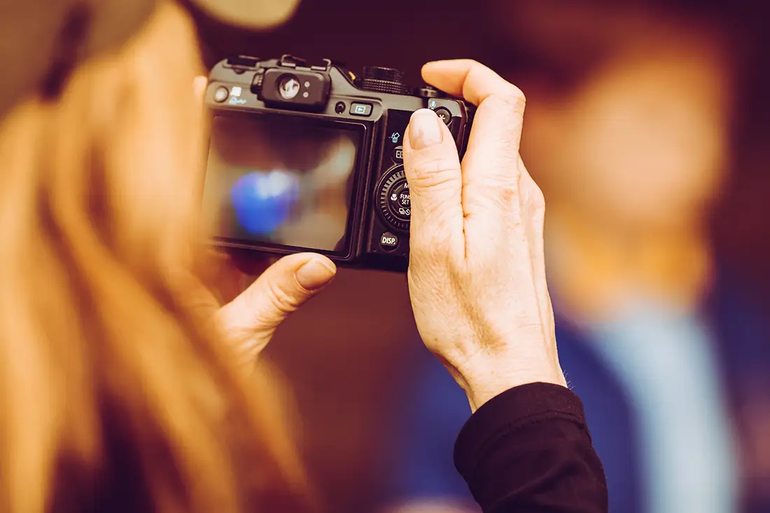 looking over the shoulder of a woman holding a digital camera