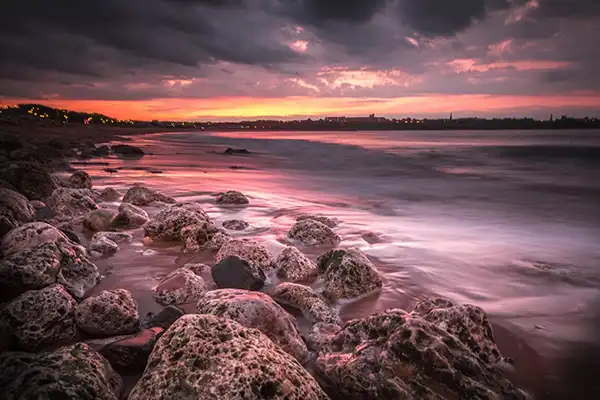 Long exposure on water at a rocky beach near sunset