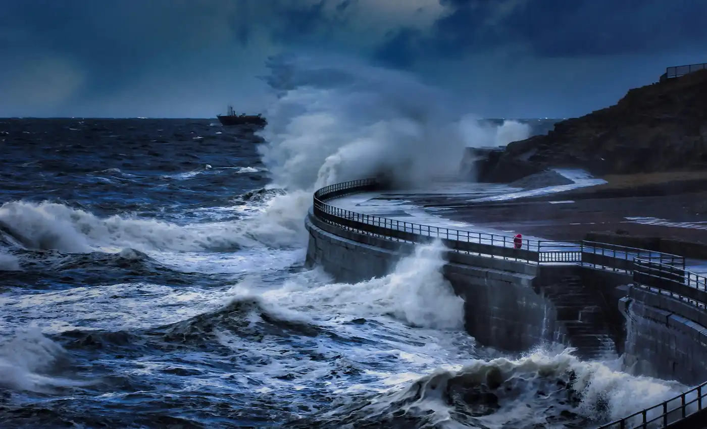 Waves crashing against sea wall in stormy weather