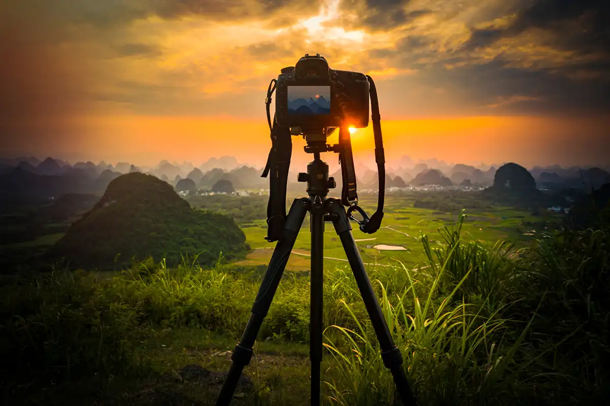 A camera on a tripod facing a sunset