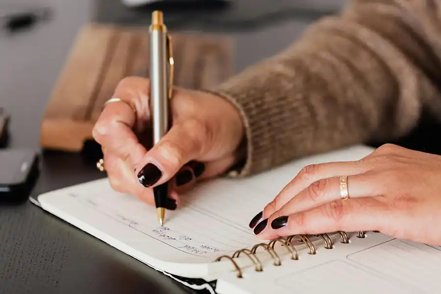 person writing on a paper with a pen