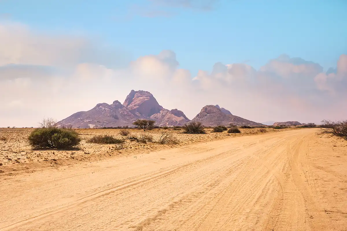 A desert road with mountains the background