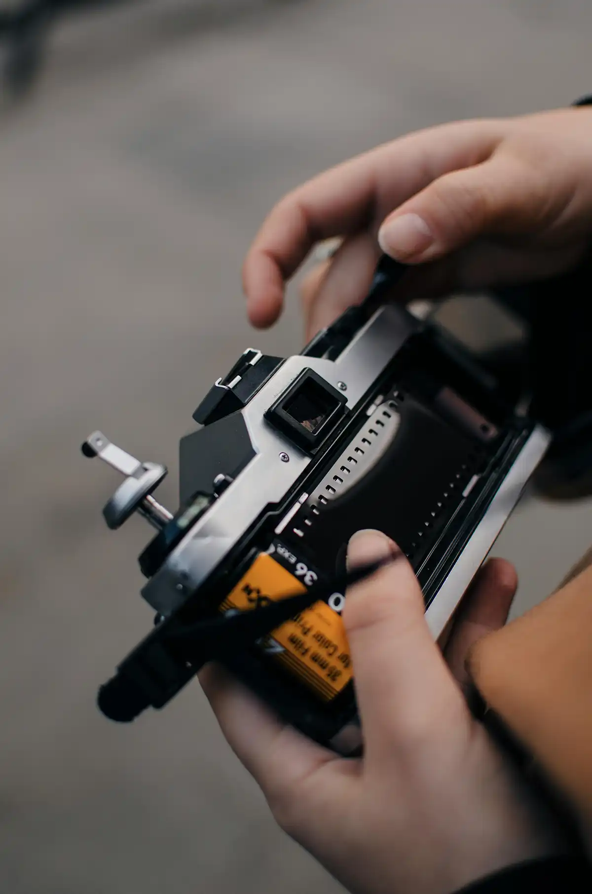A 35mm film cannister being loaded into the back of a film camera