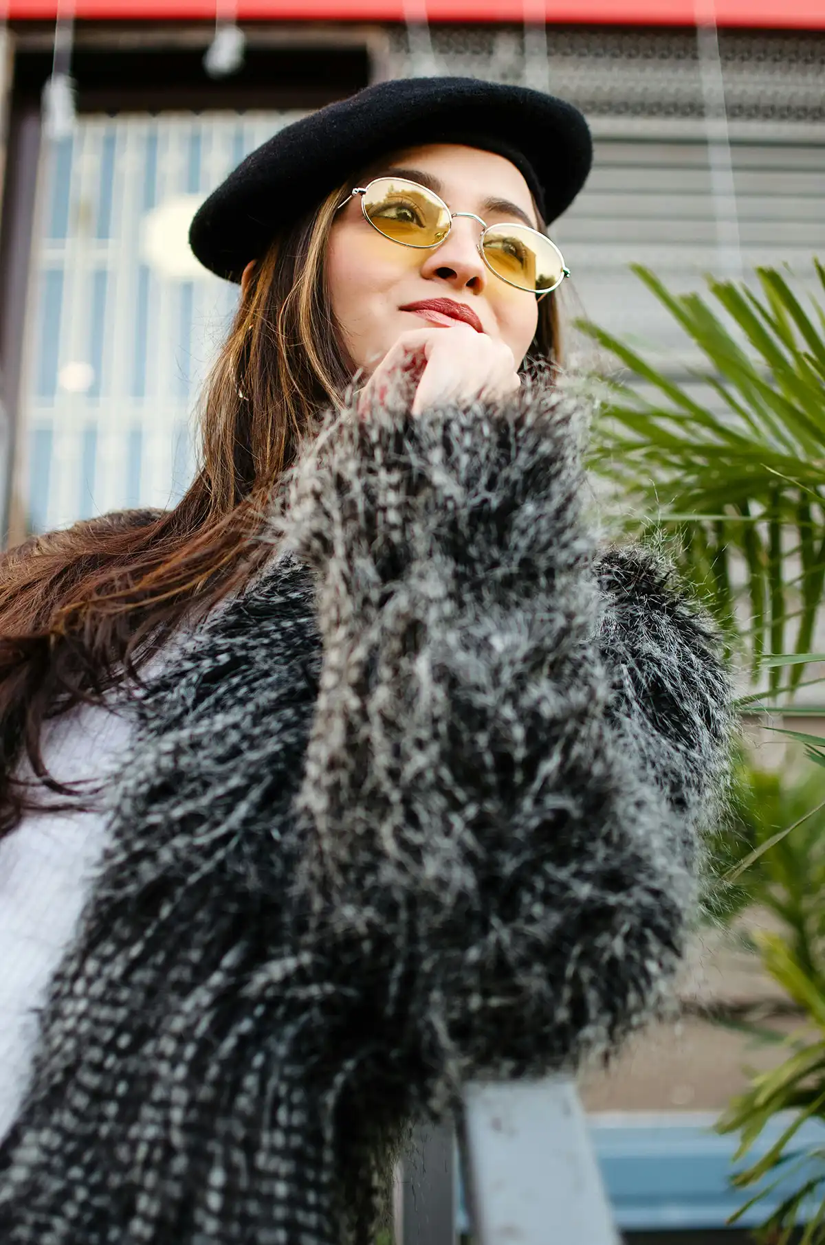 A female model wearing yellow glasses and black french beret