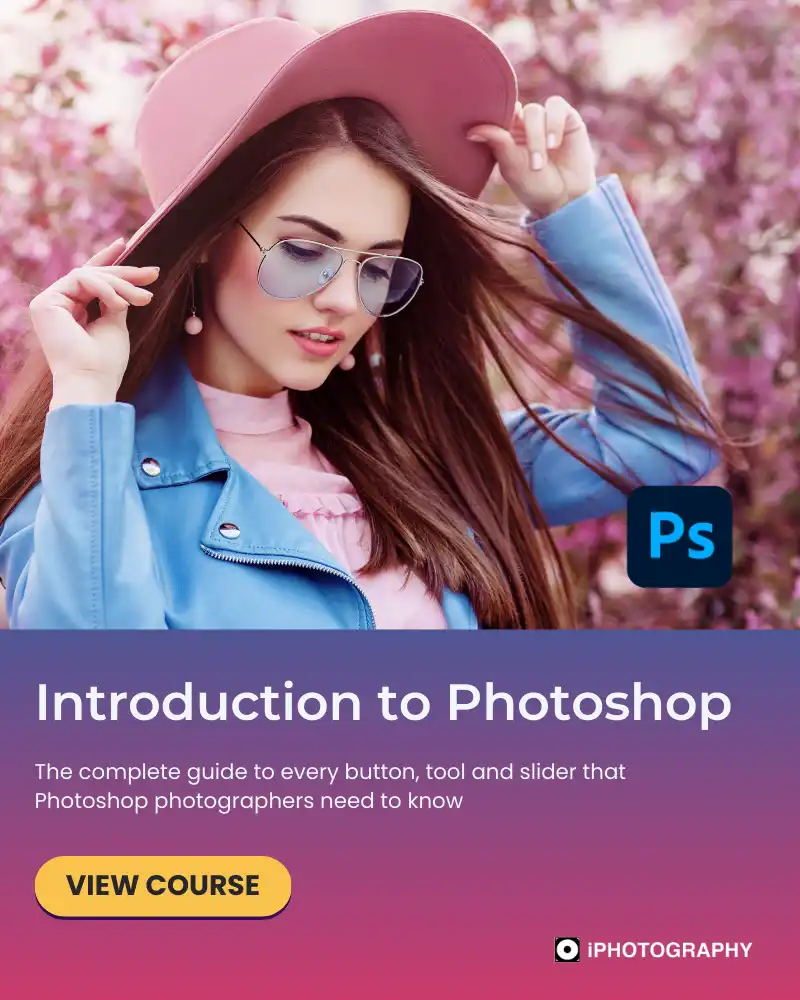a woman in a large pink hat wearing glasses and a blue denim jacket in front of a pink flowering tree
