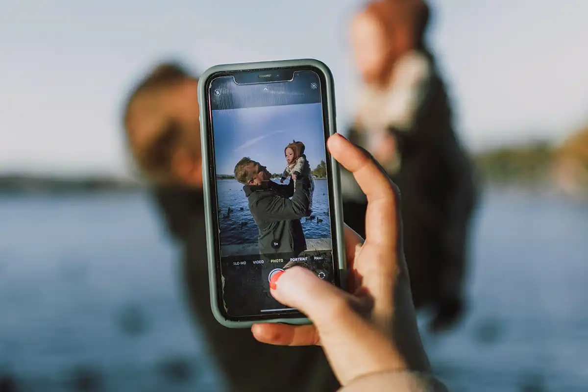 Smartphone displaying an image of an father lifting up a child in front of a lake