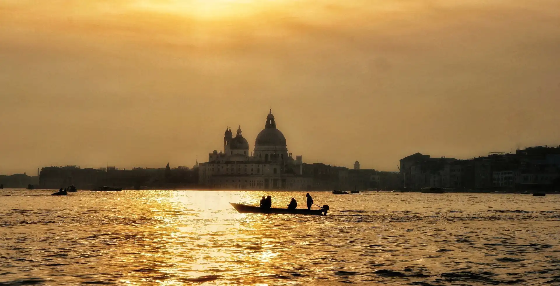 a boat on a river in silhouette in front of a city