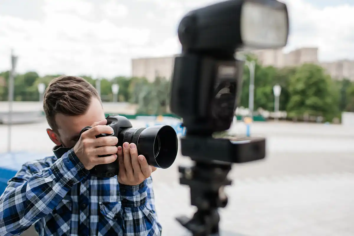 A man taking a photo with an off camera flash on a stand in the foreground