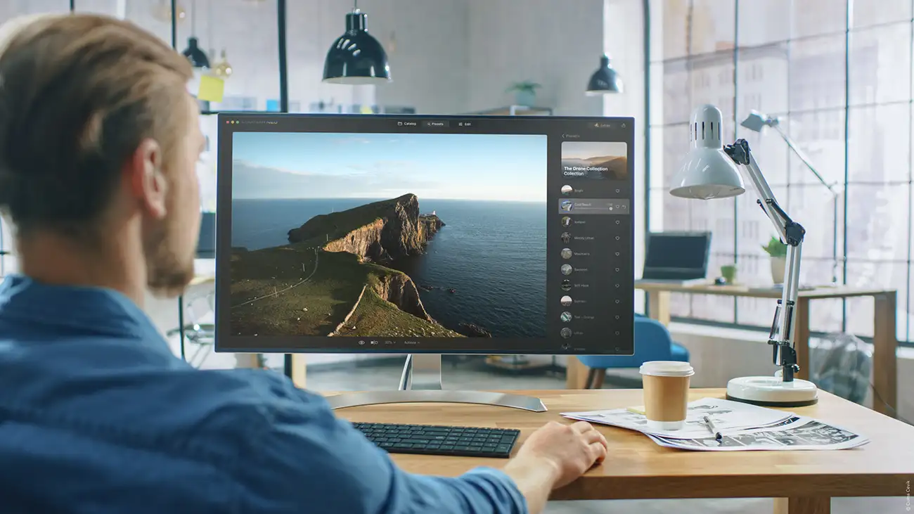 man sat a computer editing a landscape photo on luminar neo