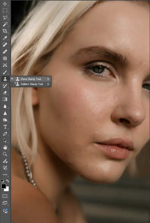 A screen shot of the photoshop vertical toolbar with the clone stamp tool highlighted in front a model's photo