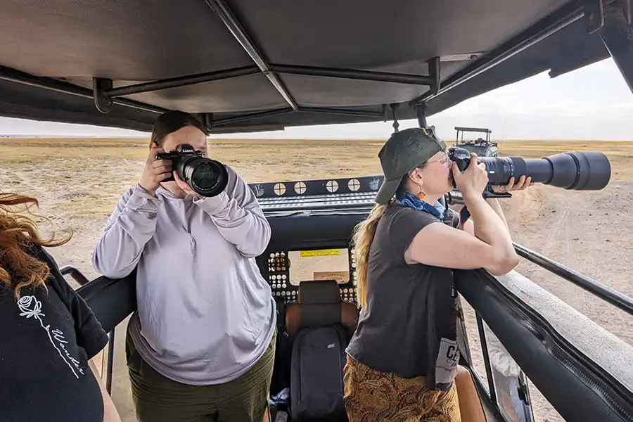 two photographers holding cameras in a safari game truck