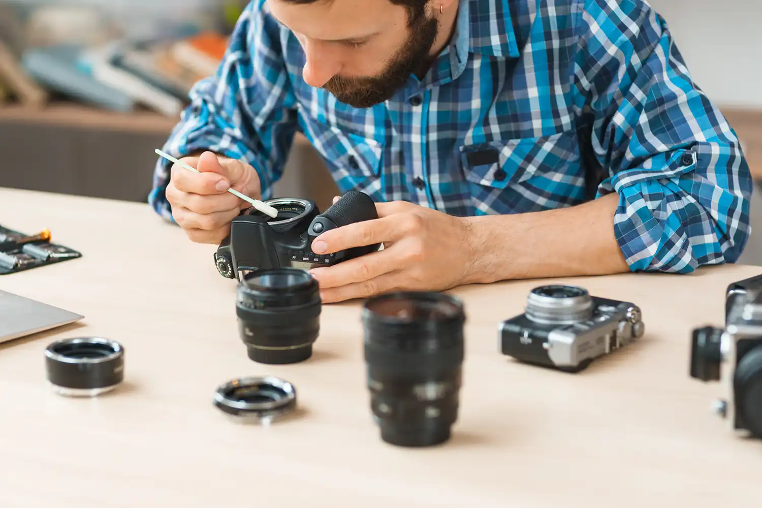 a man sat at a table cleaning the sensor of a digital camera