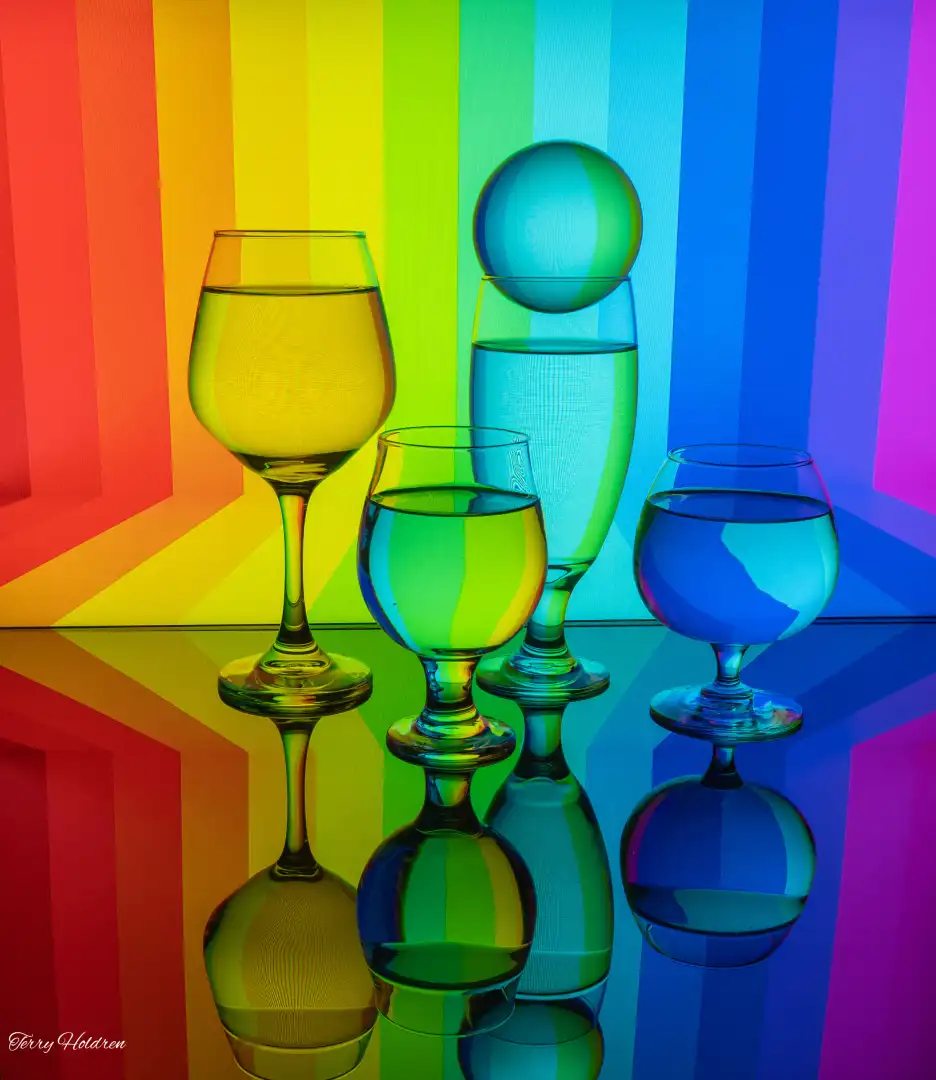 4 glasses of water in front of a colourful LED rainbow screen
