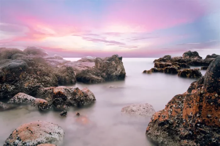 a long exposure photograph of rocks in the sea