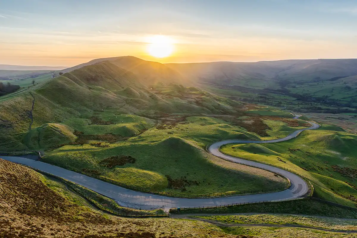 Winding road through a valley landscape at golden hour