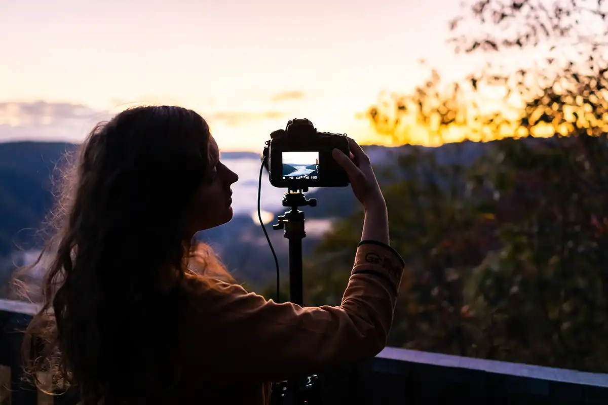 woman changing camera settings at sunset