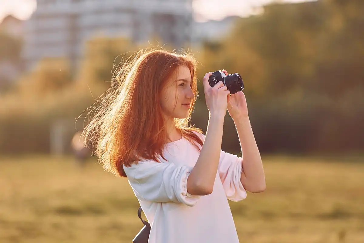 Woman taking photo at golden hour in a white top