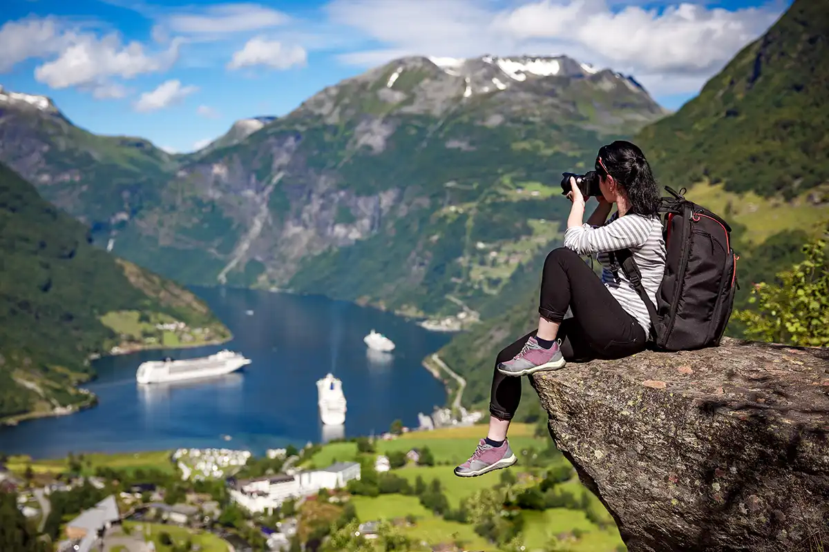 Woman taking photo on rock ledge
